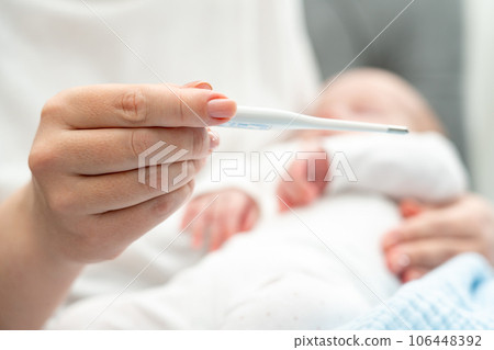 Mother evaluates newborn's health with a thermometer, Concept of infant care and safety 106448392