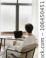 Back view of middle aged business woman using laptop sitting near the window. 106450451