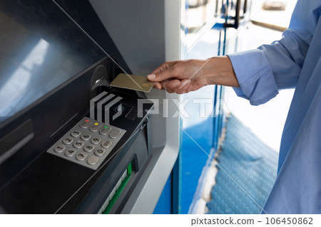 close-up of a woman inserting a bank card into an ATM 106450862