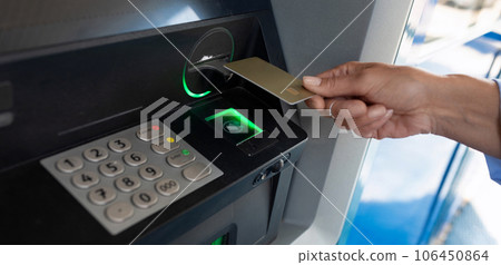 female hand applies a bank card to an ATM 106450864