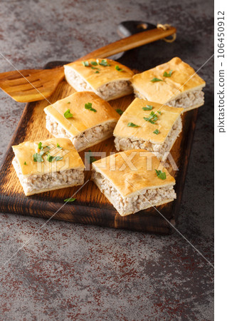 Delicious sliced italian sausage mince pie with cream cheese close-up on a wooden board. Vertical Delicious sliced italian sausage mince pie with cream cheese close-up on a wooden board. Vertical 106450912
