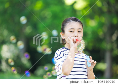 Elementary school girl playing with soap bubble Elementary school girl playing with soap bubble 106450950