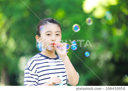 Elementary school girl playing with soap bubble Elementary school girl playing with soap bubble 106450958