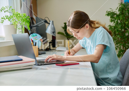 Preteen girl studying at home at her desk using a laptop computer 106450966