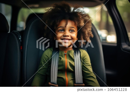 African American girl in a child car seat wearing a seatbelt while traveling by car. 106451228