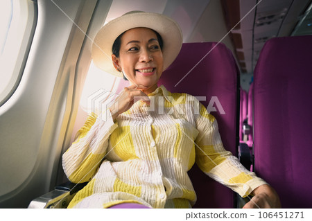 Happy middle age woman in summer clothing traveling by plane. Holidays and transportation concept Happy middle age woman in summer clothing traveling by plane. Holidays and transportation concept 106451271