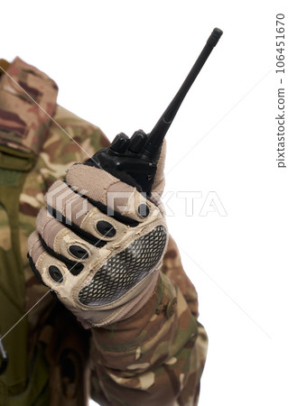 Unrecognizable man in camouflage uniform holding military walkie-talkie indoor. Close up view of portable radio sets, held by military soldier, isolated on white studio background. Connection concept. 106451670