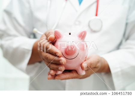 Asian woman doctor holding piggy bank, cost of treatment or education concept. 106451780