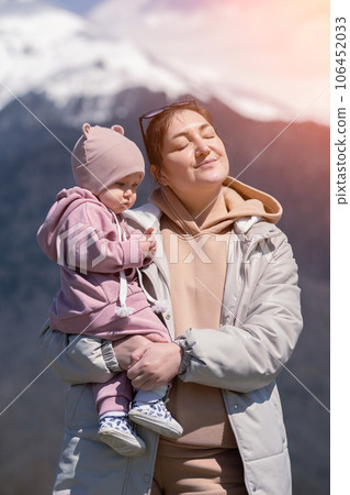 Mother holds in arms toddler daughter playing with dandelion 106452033
