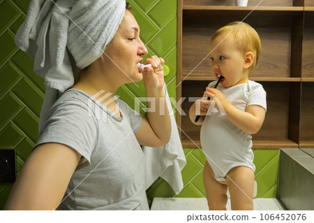 Young mother and toddler brush teeth in apartment bathroom 106452076