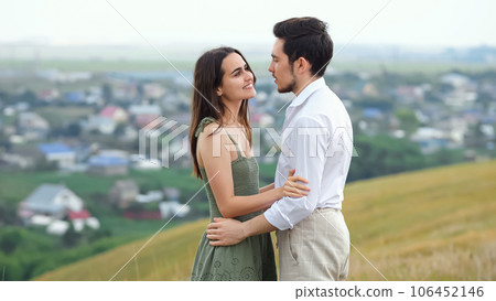 Happy couple of man and woman stands on hill kissing 106452146