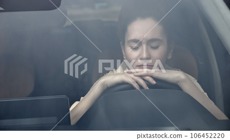 Woman sits in car with sad expression view through windshield 106452220