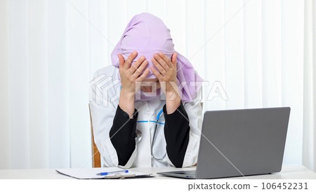 Muslim woman in doctor suit works with tired expression 106452231