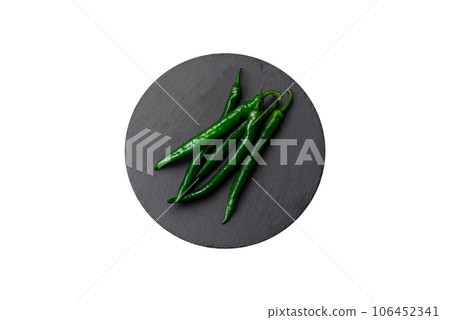 Fresh hot green chili peppers on a dark concrete background Fresh hot green chili peppers on a dark concrete background 106452341