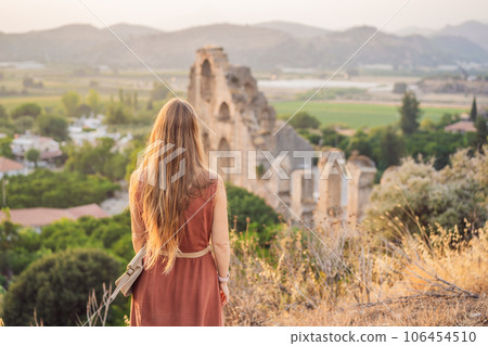 Woman tourist explores Aspendos Ancient City. Aspendos acropolis city ruins, cisterns, aqueducts and old temple. Aspendos Antalya Turkey. turkiye 106454510