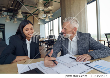 Two business colleagues talking in meeting room during work on project. Teamwork concept Two business colleagues talking in meeting room during work on project. Teamwork concept 106454513