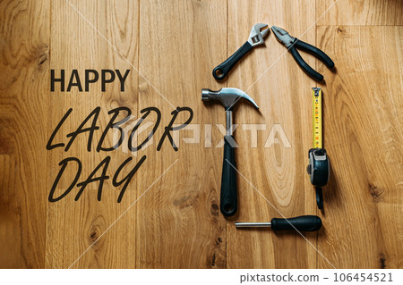 Happy labor day banner with different construction tools on wooden background. Construction and manufacturing tools on wooden background. Labor day background concept. Happy labor day banner with different construction tools on wooden background. Construction and manufacturing tools on wooden background. Labor day background concept. 106454521