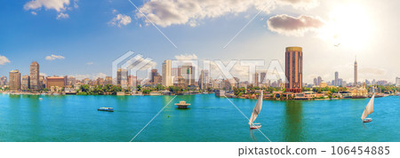 Nile River waters, traditional felucca boats and famous city buildings of Cairo, Egypt Nile River waters, traditional felucca boats and famous city buildings of Cairo, Egypt 106454885