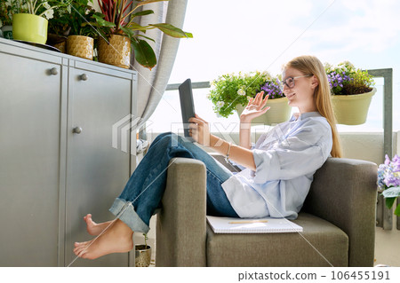 Smiling teenage girl using digital tablet, waving hand greeting at screen 106455191