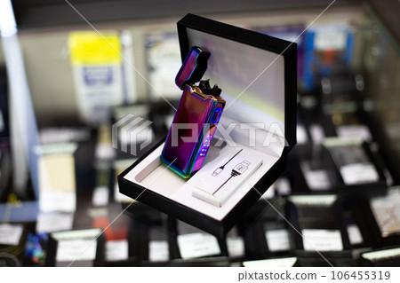 Electronic purple gradient lighter with a usb charger is open standing on a glass in a showcase in a tobacco shop Electronic purple gradient lighter with a usb charger is open standing on a glass in a showcase in a tobacco shop 106455319