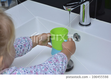 girl holding a glass in her hands and pouring water Faucet girl holding a glass in her hands and pouring water Faucet 106455598