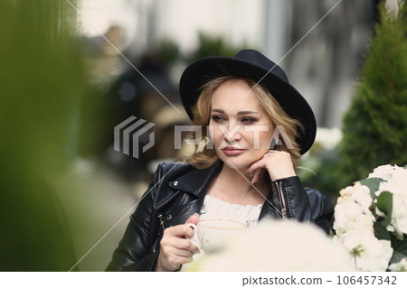 blond woman in black leather jacket, black hat close up photo in summer terrace blond woman in black leather jacket, black hat close up photo in summer terrace 106457342