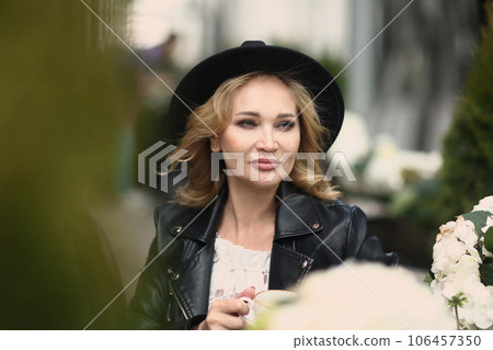 blond woman in black leather jacket, black hat close up photo in summer terrace blond woman in black leather jacket, black hat close up photo in summer terrace 106457350