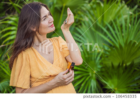 pregnant woman after 40 demonstrating the use of an aroma pendant, combining style and aromatherapy during her pregnancy journey 106458335