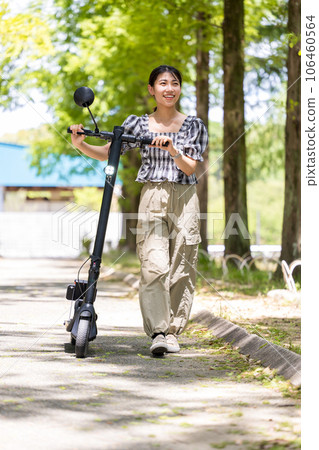 一位年輕可愛的女士在電動浮板上散步，沐浴在透過樹林的清爽陽光下 | 電動浮板圖片 106460564
