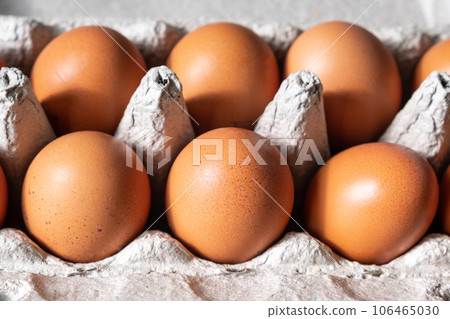 A few brown eggs among the cells of a large cardboard bag, a chicken egg as a valuable nutritious product, a tray for carrying and storing fragile eggs. A full package of eggs, an important food item 106465030