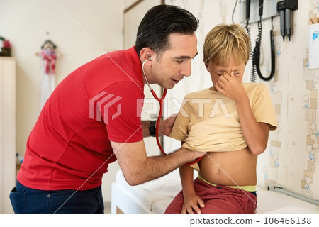Male Doctor Examining Boy. Pediatrician examining boy patient with stethoscope. 106466138