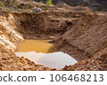 A large hole dug in sandy soil and flooded with water 106468213
