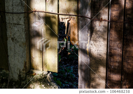 Wooden fence with broken boards. Hole in a wooden fence 106468238