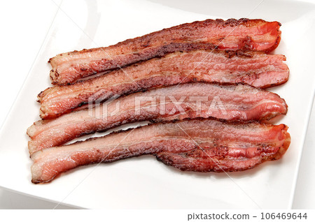 thinly sliced bacon fried in a frying pan 106469644