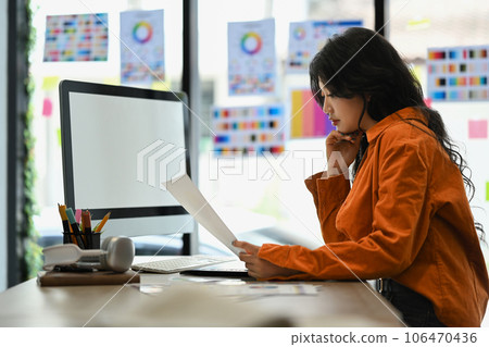 Side view of young startup businesswoman, graphic designer working at modern workplace 106470436