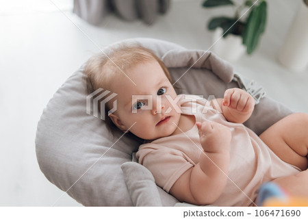 Adorable baby lying in a baby bassinet with a rattle in the room. High quality photo 106471690