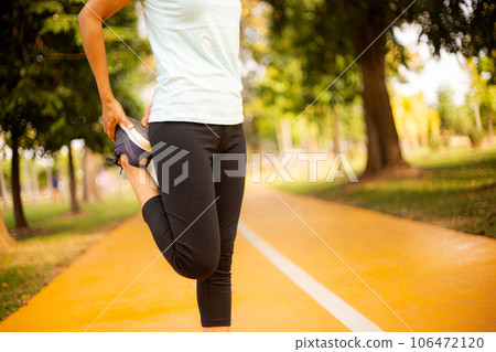 Young female stretching before fitness training session at the park. on the blue running track , green tree bokeh and green grass background at sunset. Young female stretching before fitness training session at the park. on the blue running track , green tree bokeh and green grass background at sunset. 106472120