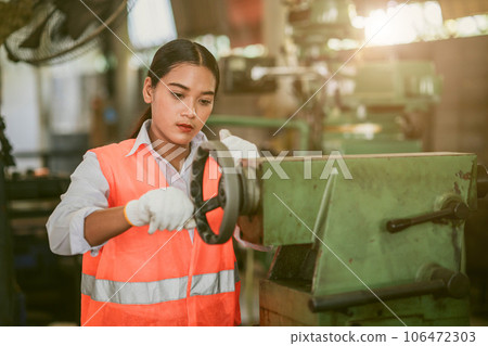 woman worker hard work focus working in heavy metal machine lathe milling factory industry 106472303