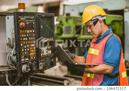 Engineer worker check service panel program operate CNC lathe machine with laptop computer fix repair old machine. Engineer worker check service panel program operate CNC lathe machine with laptop computer fix repair old machine. 106472317