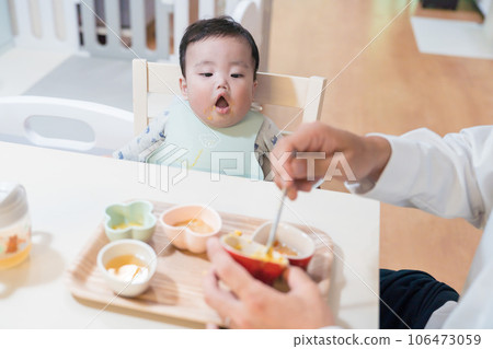 An 8-month-old baby in a good mood after being fed baby food by his father An 8-month-old baby in a good mood after being fed baby food by his father 106473059