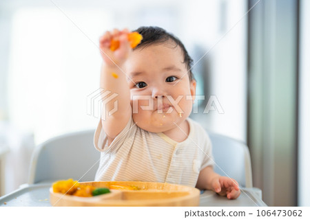 A 9-month-old baby who is in a good mood after grabbing and eating in the late stage of baby food A 9-month-old baby who is in a good mood after grabbing and eating in the late stage of baby food 106473062