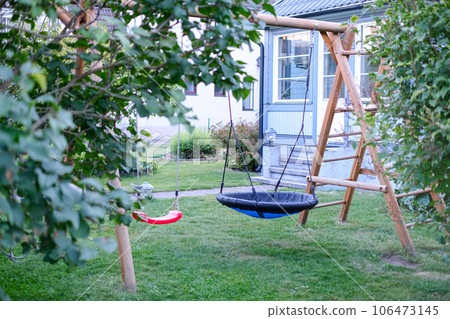 Private house backyard featuring garden trees and a swing in centre 106473145