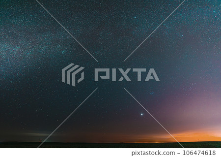 Night Starry Sky With Glowing Stars Above Countryside Field Landscape In Early Spring. Bright Glow Of Planet Venus In Sky Among The Stars. Sky In Warm Lights Of Evening Sunset Dawn Or Morning Sunrise Night Starry Sky With Glowing Stars Above Countryside Field Landscape In Early Spring. Bright Glow Of Planet Venus In Sky Among The Stars. Sky In Warm Lights Of Evening Sunset Dawn Or Morning Sunrise 106474618