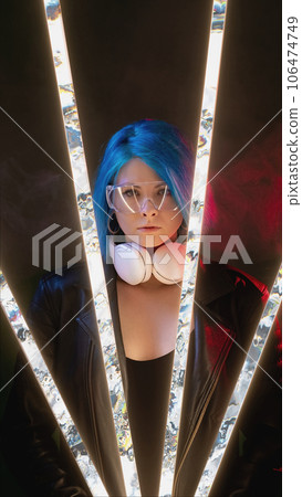 Cyberpunk people. Futuristic portrait. Vaporwave party night. Confident DJ woman with blue hair goggles headphones on pink neon light glitch illumination smoke dark background. Cyberpunk people. Futuristic portrait. Vaporwave party night. Confident DJ woman with blue hair goggles headphones on pink neon light glitch illumination smoke dark background. 106474749