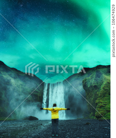 Female tourist enjoying with Skogafoss waterfall and northern lights glowing in the night 106474929