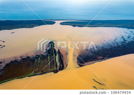 Yellow river tributary sulfur rich sediment from the volcanic area flowing through black sand beach to the ocean in wilderness at Iceland 106474934