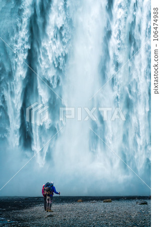 Backpacker couple standing at powerful waterfall in summer 106474988