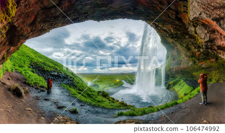 Natural cave with Seljalandsfoss waterfall flowing and tourist enjoying in summer at Iceland Natural cave with Seljalandsfoss waterfall flowing and tourist enjoying in summer at Iceland 106474992