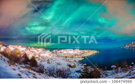 Aurora borealis glowing over scandinavian village on coastline in winter at Lofoten Islands 106474999