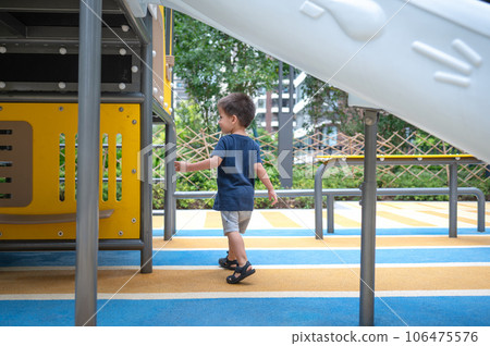 A toddler is playing on toys in the park 106475576
